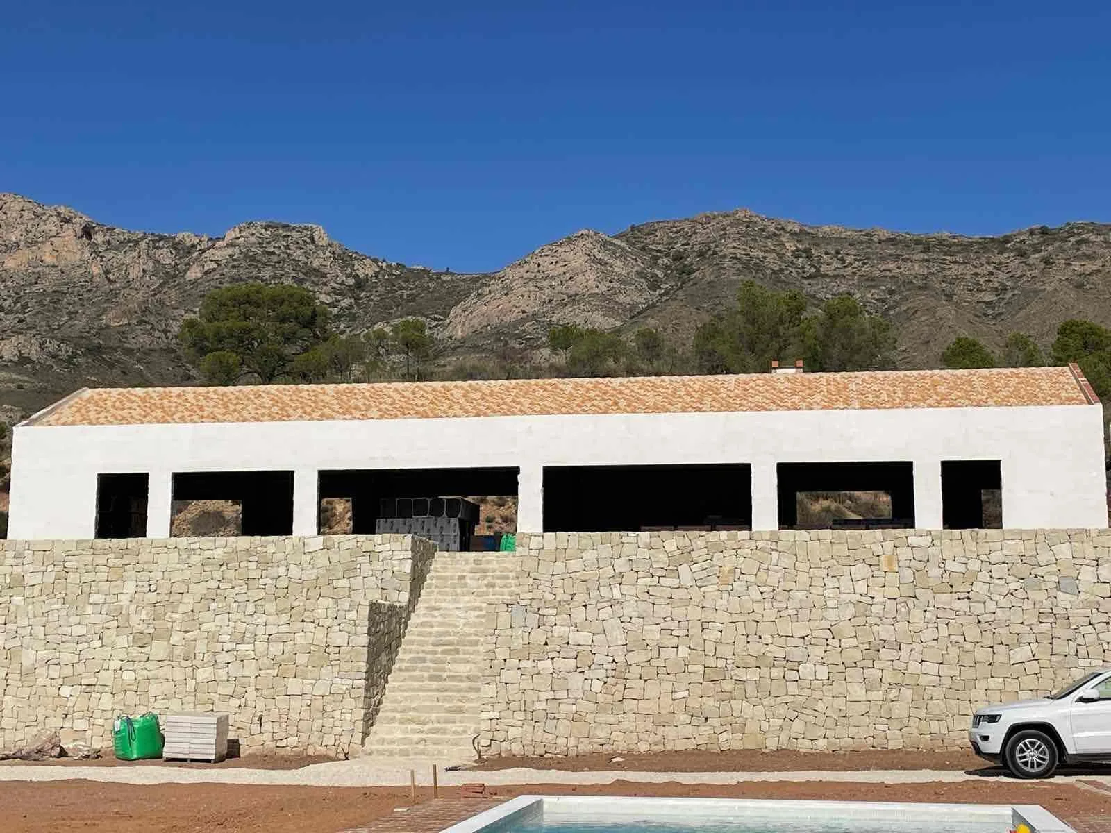 Het afgewerkte huis met de natuurstenen muur en het zwembad